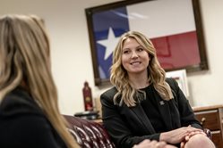 two females sitting and talking with Texas state flag in the background